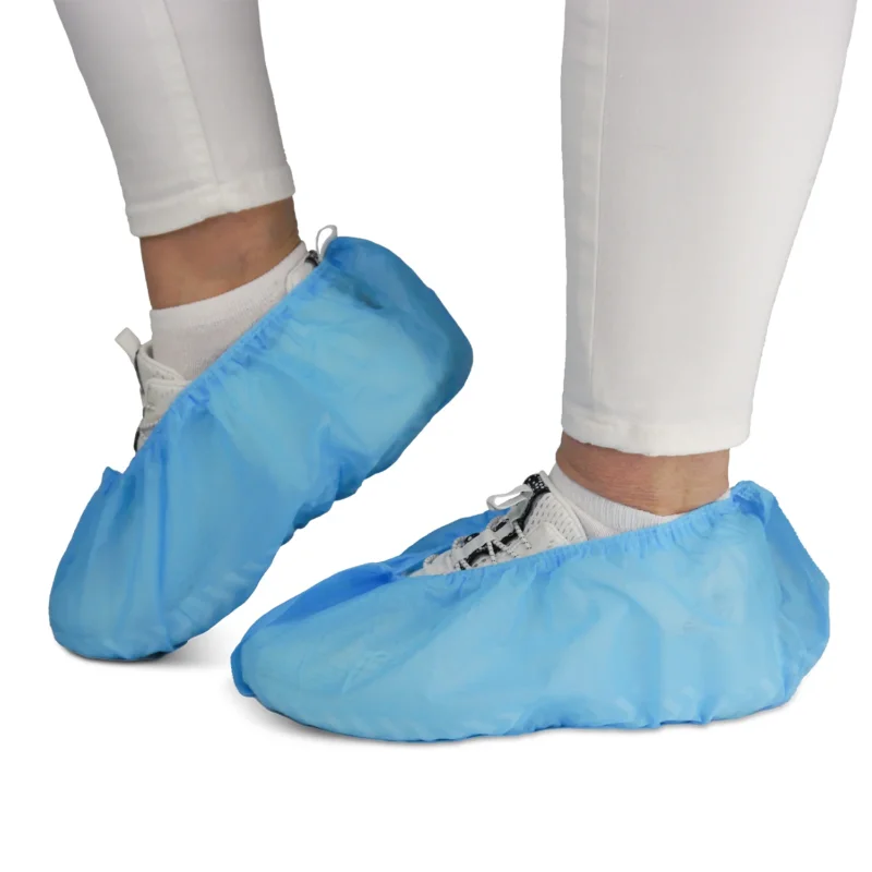 Eine Person trägt weiße Hosen und Sneaker mit ARNOMED ABS Schuhüberziehern von ARNOWA GmbH. Die rutschfesten Einweg-Überzieher (Beutel à 100 Stück) schützen Schuhe und Böden - ideal für hygienische Umgebungen.